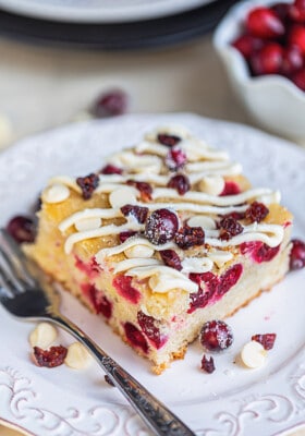 Close-up view of a square of cranberry cake on a white square plate