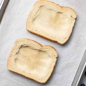 Two slices of untoasted slices of gluten free bread with a square indent on a baking sheet