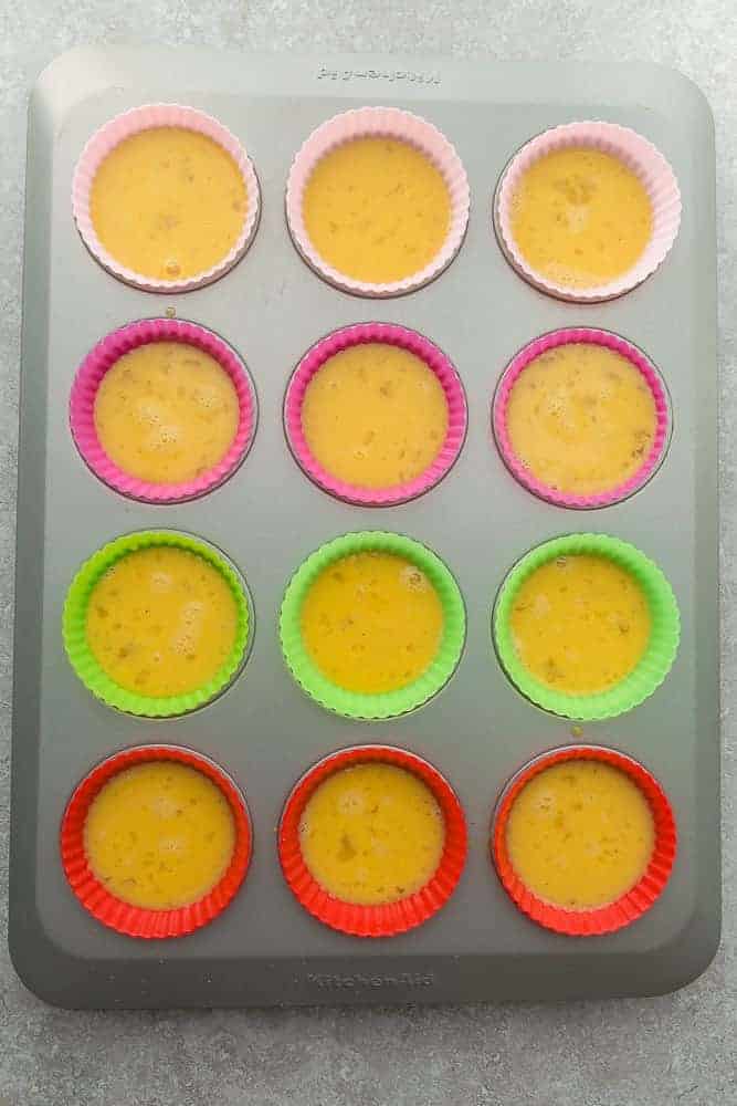 12 Silicone Liners in a Baking Pan Filled Two Thirds of the Way Full with Egg Muffin Batter