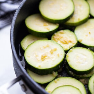 Side view of raw zucchini rounds in a large nonstick pan
