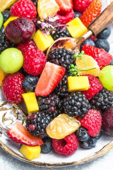 Close-up view of rainbow fruit salad in an oval platter with a spoon
