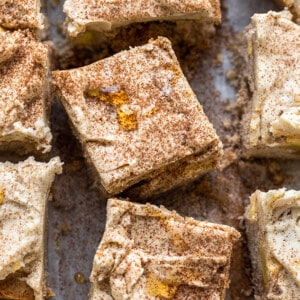 Close-up of frosted squares of apple cake topped with cinnamon