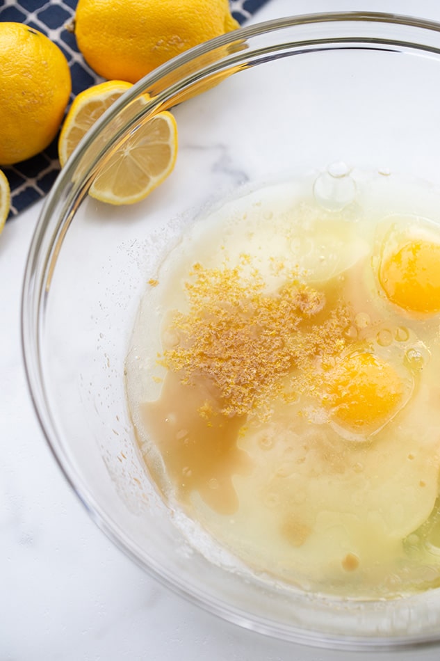 A bowl of eggs and melted coconut oil, with lemons in the background
