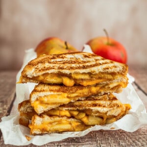 Side shot of grilled cheese sandwich halves stacked on top of white parchment paper
