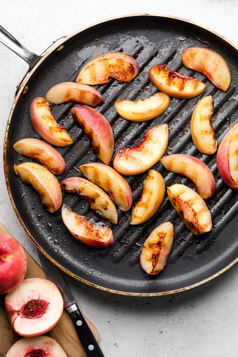Top view of sliced grilled peaches on a grill pan