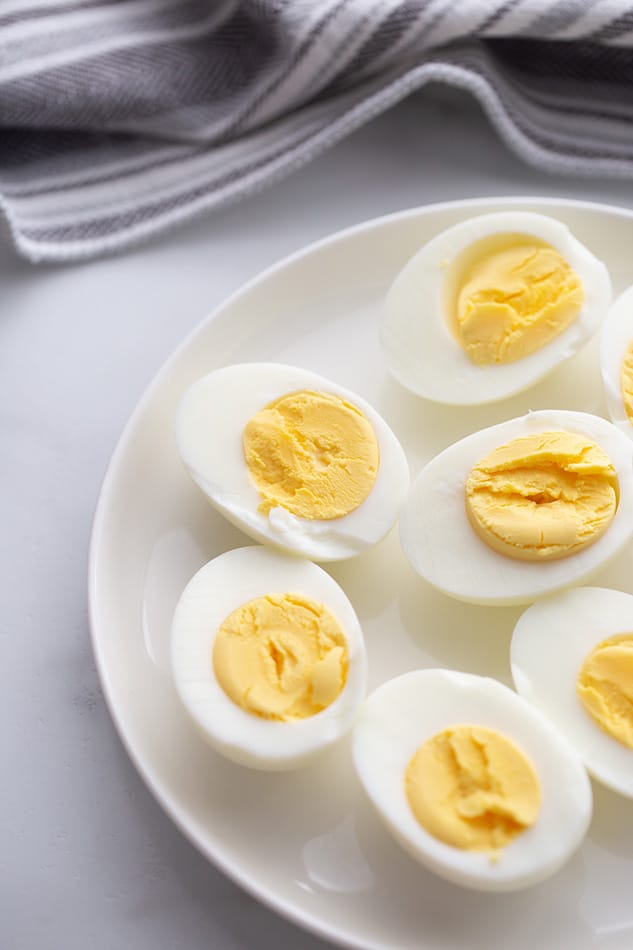 Unseasoned Hard Boiled Egg Halves on a White Plate in Front of a Cloth Napkin