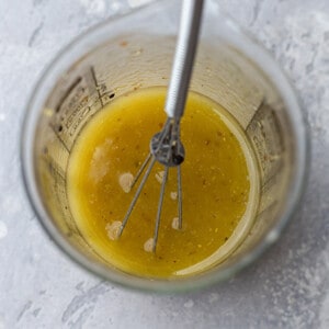 Overhead view of lemon vinaigrette in a measuring cup with a whisk