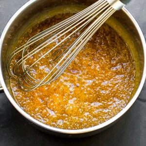 A pot of bubbling caramel sauce with a whisk
