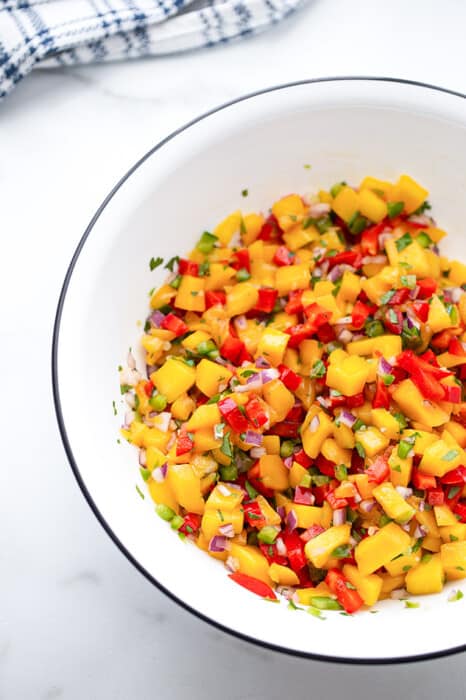 Side shot of a serving of fresh mango salsa in a white bowl