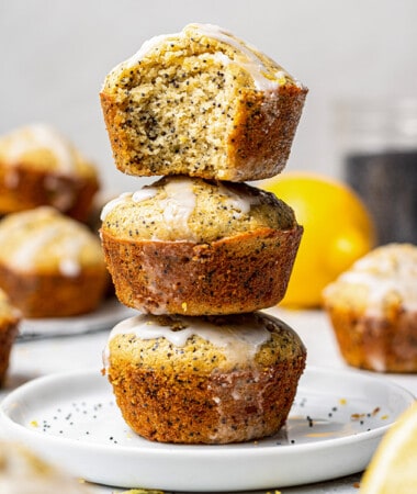 Side shot of three lemon muffins stacked on top of one another with one missing a bite
