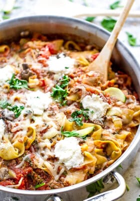 Side view of Keto Zucchini Lasagna in a stainless steel pan with a wooden spoon
