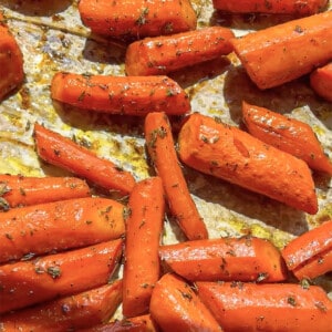 Roasted chopped carrots on a parchment lined baking sheet spread out