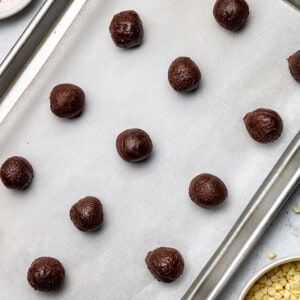 Overhead view of chocolate peppermint truffle balls on a parchment-lined baking sheet