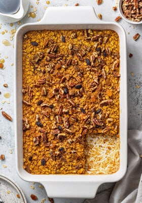 A baking dish full of pumpkin baked oatmeal with one slice missing from the bottom right corner