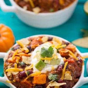 Pumpkin Chili in a crock topped with sour cream, avocado, and cilantro