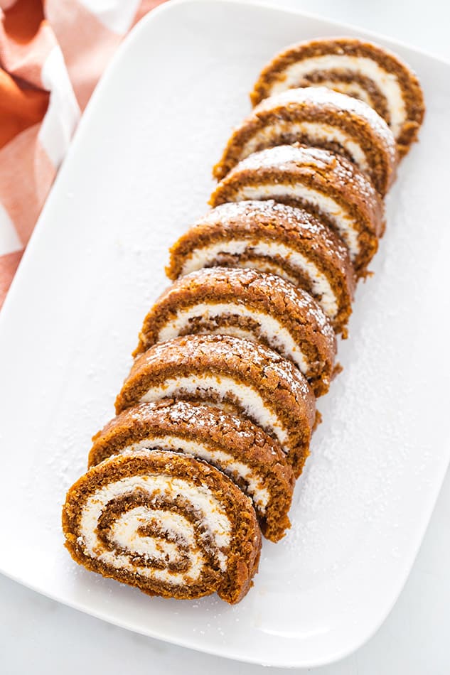 Overhead view of sliced pumpkin roll on a serving platter with powdered sugar