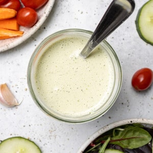 Top view of creamy ranch dressing in a glass jar with a spoon