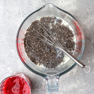 Top view of chia pudding ingredients in a large measuring cup with a whisk