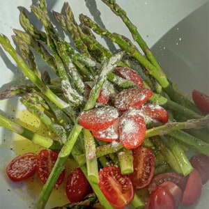 Seasoned asparagus and grape tomato halves in a bowl