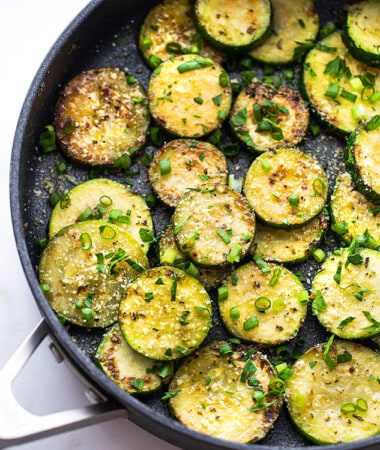 Top view of sautéed zucchini with fresh herbs in a large nonstick pan
