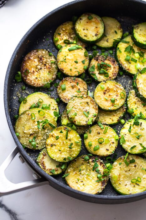 Top view of sautéed zucchini with fresh herbs in a large nonstick pan