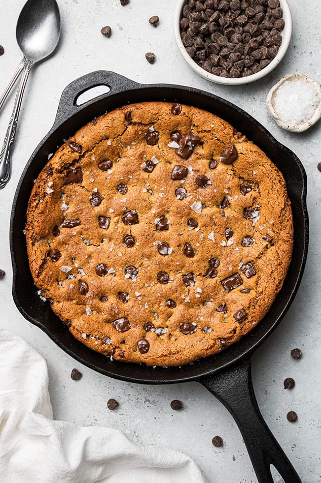 A baked skillet cookie in a cast-iron pan on top of a granite counter