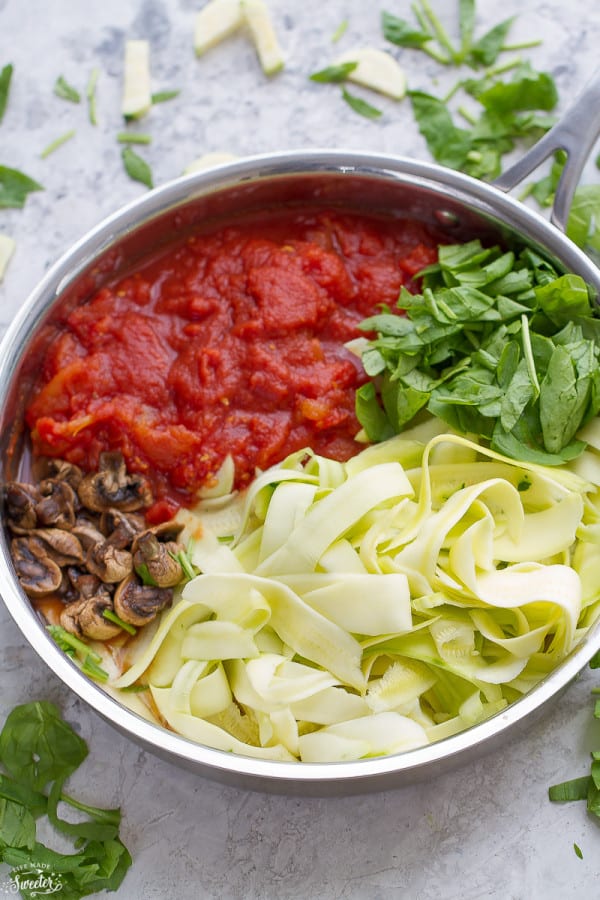 Top view of zucchini lasagna ingredients in stainless steel skillet.