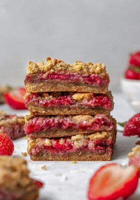 Side view of four strawberry oat crumb bars stacked on a white background