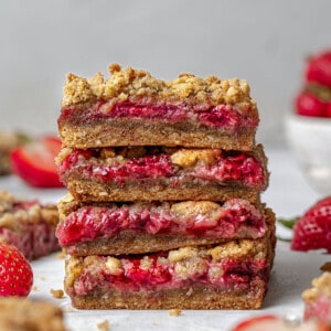 Side view of four strawberry oat crumb bars stacked on a white background