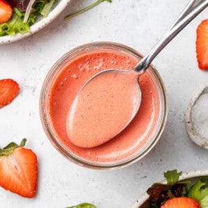 Top view of blended strawberry dressing in a glass jar with a spoon