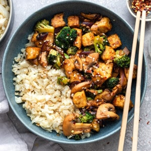 Top view of tofu stir fry in a blue bowl with chopsticks