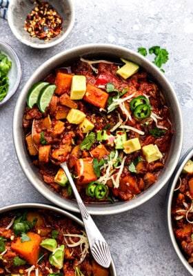 Top view of Vegan Chili in a white bowl with a spoon on a grey background