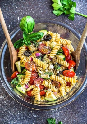 Top view of a mixing bowl with spoons of an Easy Summer Pasta Salad