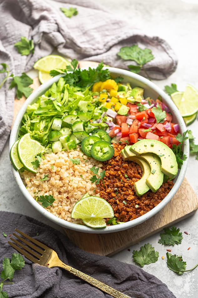 A vegan taco bowl on a cutting board with a gold fork beside it