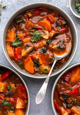 Top view of 3 bowls of vegetable stew on a grey background