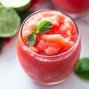 A Small Glass Filled with Watermelon Slushie and Garnished with Fresh Mint Leaves