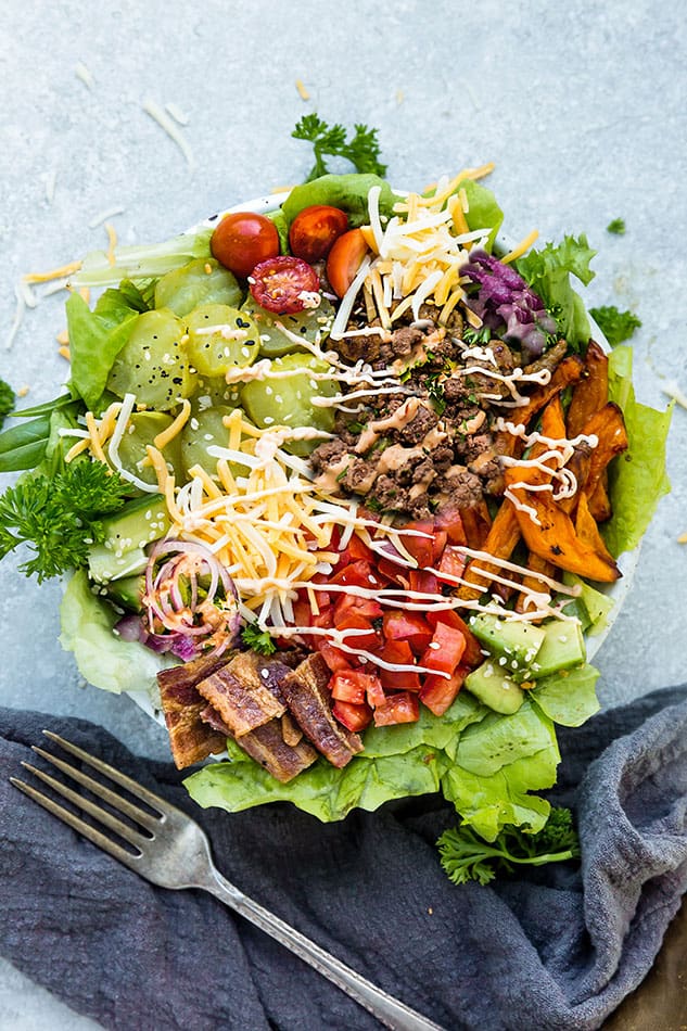 Top view of keto burger in a bowl in a white bowl with pumpkin fries on a grey background