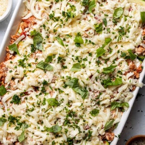 Layers of fresh zucchini ribbons, ricotta mixture, cheese and bolognese sauce in a square baking casserole