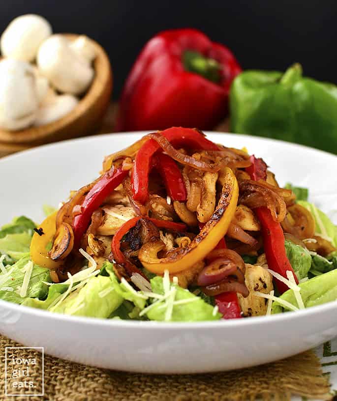 Side view of Fajita Caesar Salad topped with bell peppers and onions