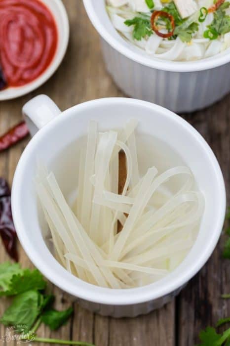 Top view of rice noodles and a cinnamon stick in a mug
