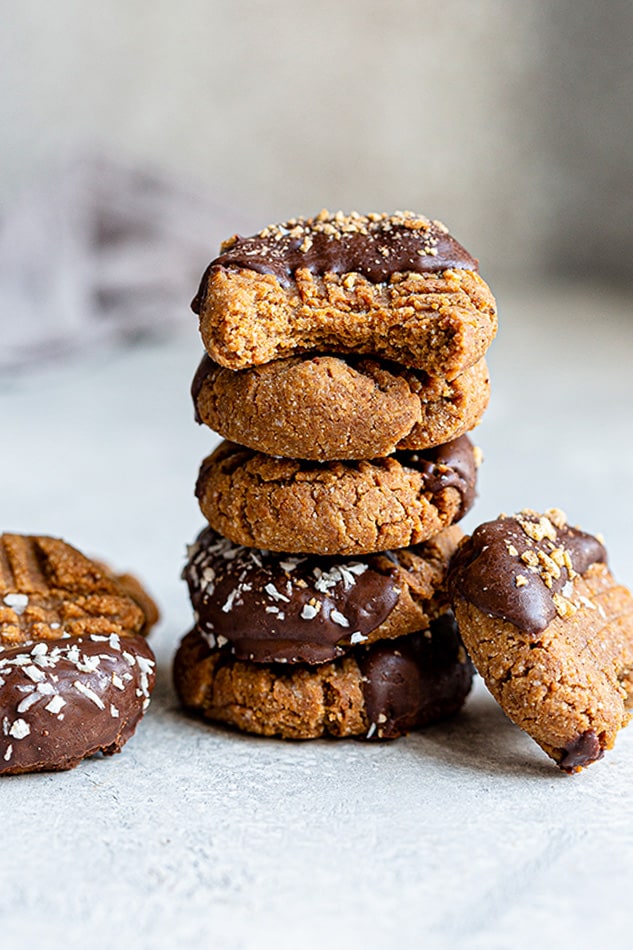 A stack of chocolate-dipped Almond Flour cookies with a bite out of one