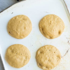 Top view of 4 keto pancake batter rounds on a white griddle pan