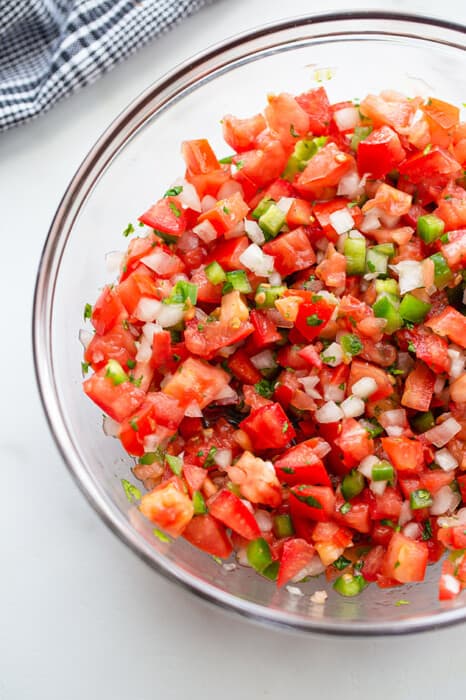 Close-up shot of a serving of fresh tomato salsa in a clear mixing bowl