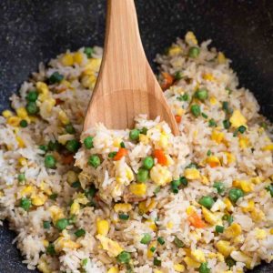 Top close-up view of egg fried rice in a wok with a wooden spoon