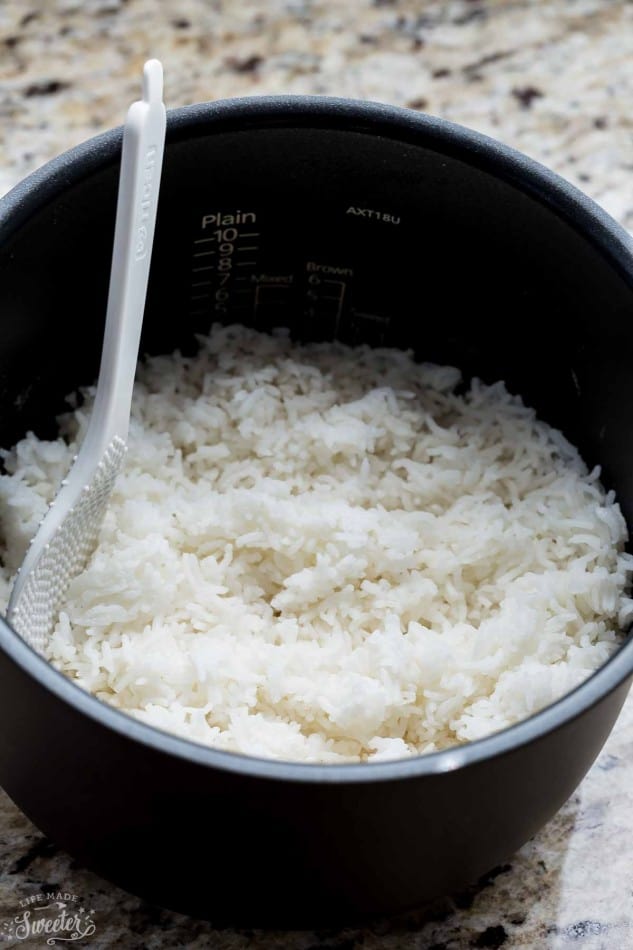 Cooked white rice in a rice cooker bowl with a spoon