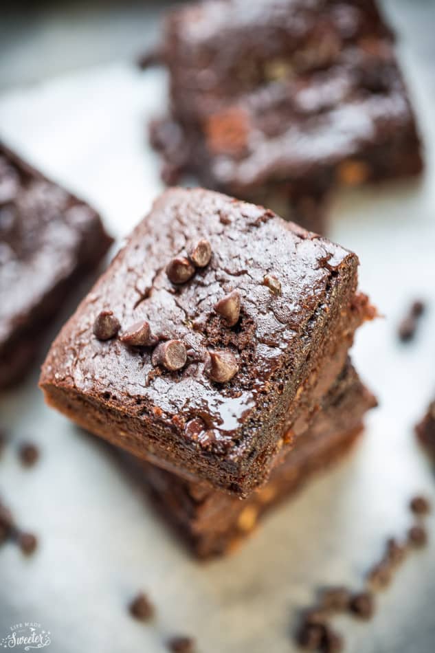 Close up view of stack of 2 almond flour brownies on a white background with chocolate chips