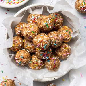 Overhead view of a pile of birthday cake bliss balls in a white bowl