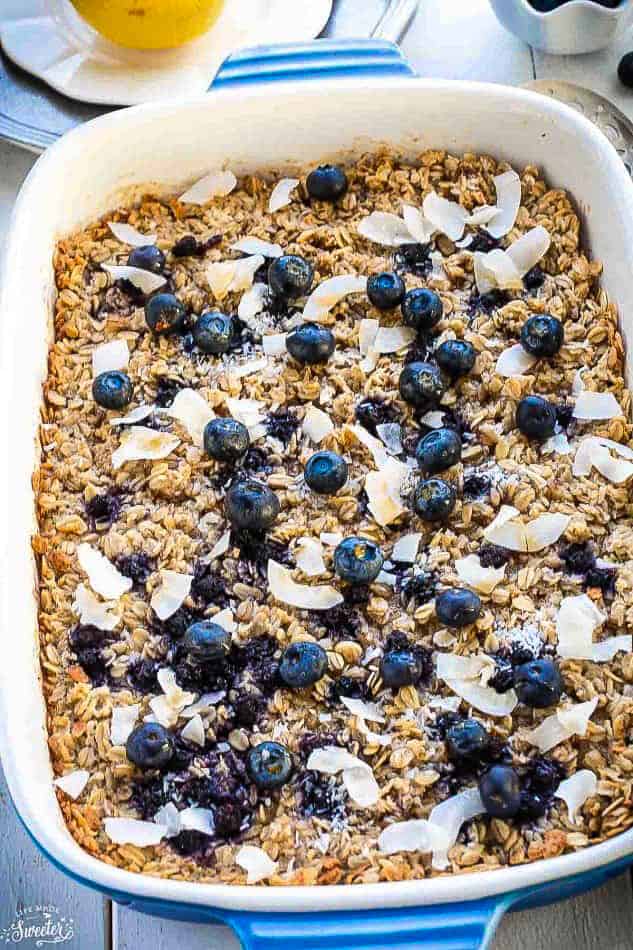 A close-up shot of blueberry baked oatmeal inside of a white casserole dish with blue handles