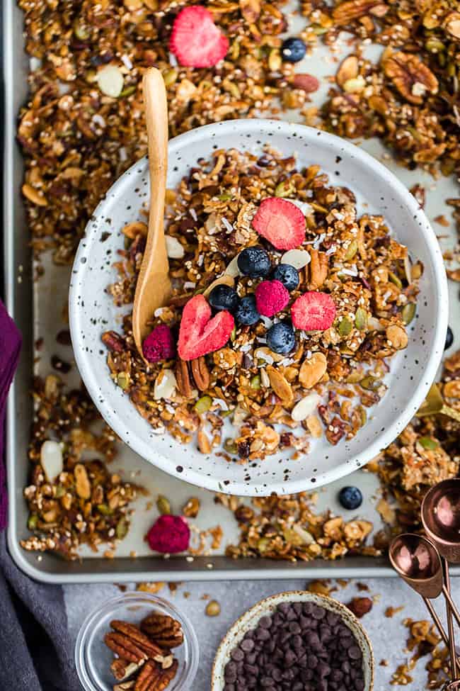 Top view of paleo granola in a white bowl with a gold spoon on a baking sheet
