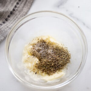 Top view of garlic herb butter in a clear bowl